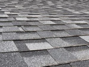 Newly installed gray dimensional asphalt shingles in staggered pattern on roof