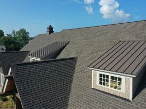 Residential roof with gray asphalt shingles and standing seam metal roofing on addition