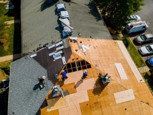 Aerial view of residential roof with new plywood sheathing, underlayment, and roofing crew during installation