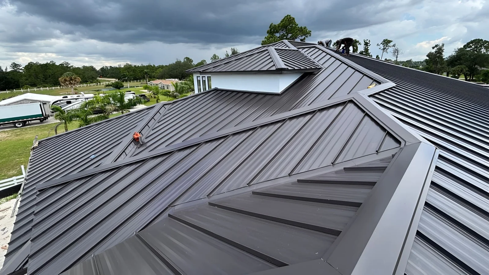 Dark gray standing seam metal roof with multiple planes, skylights, and professional flashing details