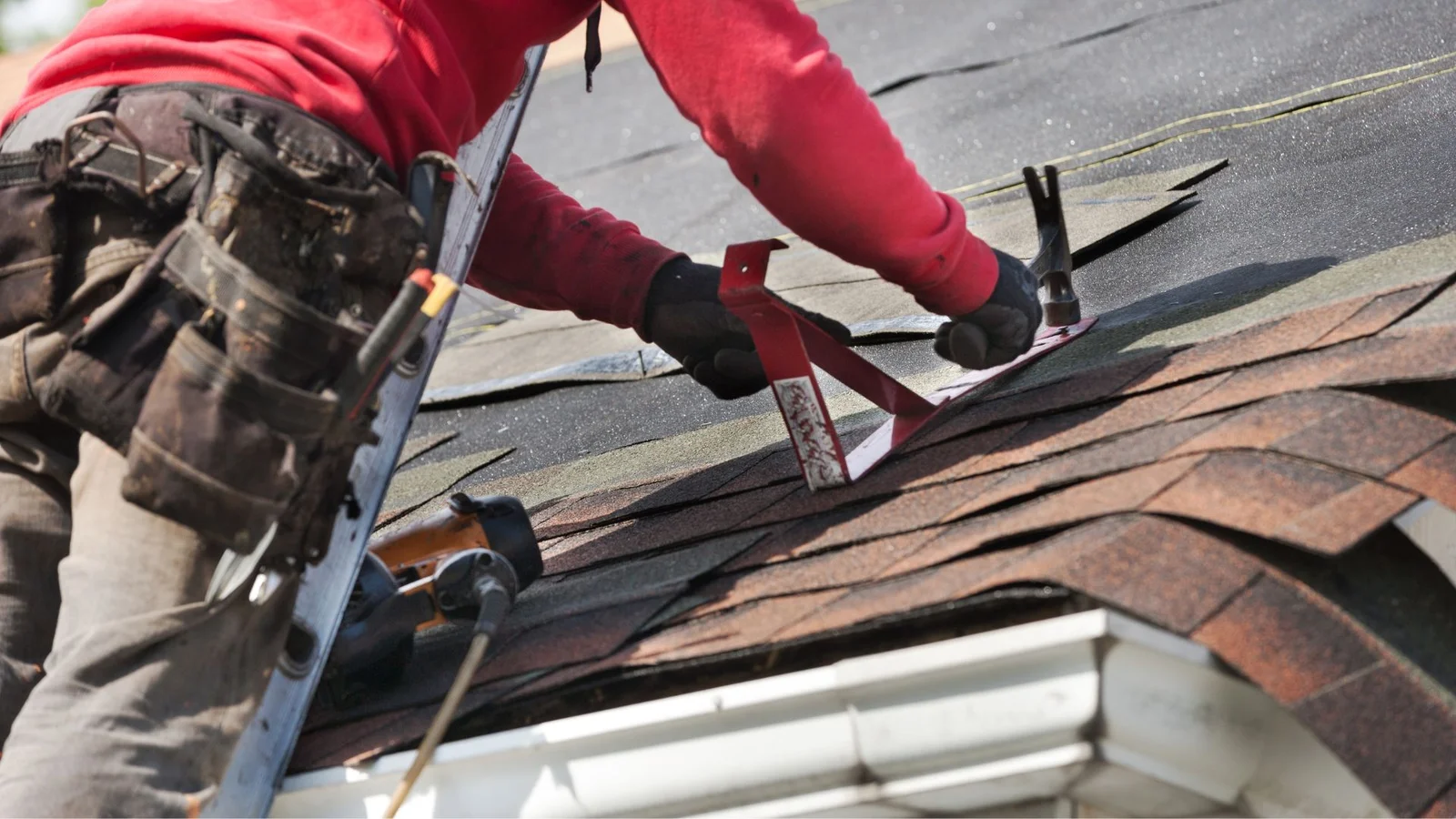 Roofer installing asphalt shingles on residential roof with brown and gray tones
