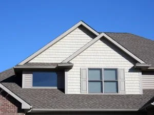 Residential roof with gray architectural shingles, gable and hip design, brick and siding exterior